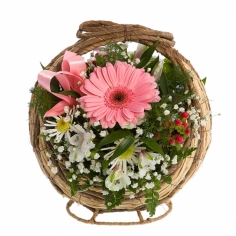 A basket of pink and white gerbera daisies, parrot flowers and chrysanthemums with green fillers