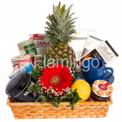 Tea, tea mug, sweets and fruit arranged in a basket