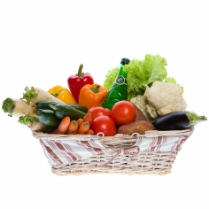 A basket of fresh vegetables of different kinds and a bottle of mineral water