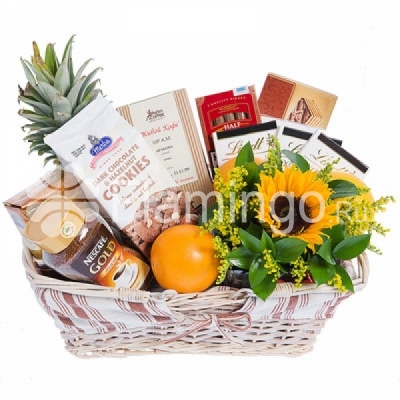 A basket with coffee, fruit and sweets