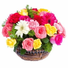 A bright basket arrangement of multicolored roses, carns and gerberas