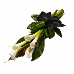 A funeral bouquet of calla lilies and green fillers tied with a black bow